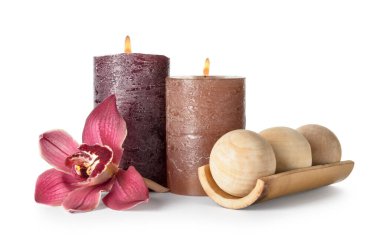 Beyaz arka planda yanan mumlar, masaj topları ve orkide çiçekli kompozisyon