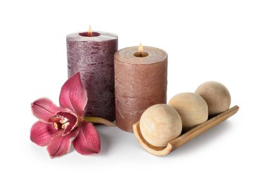 Beyaz arka planda yanan mumlar, masaj topları ve orkide çiçekli kompozisyon