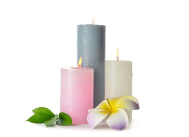 Composition with burning candles, leaves and plumeria flower on white background