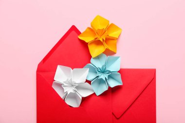 Origami daffodils and envelopes on color background