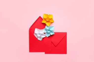 Origami daffodils and envelopes on color background