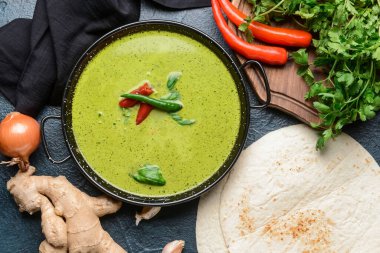 Lezzetli yeşil körili tavuk ve koyu arkaplanda malzemeler.