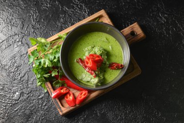 Bir kase lezzetli yeşil körili tavuk ve koyu arkaplanda malzemeler.