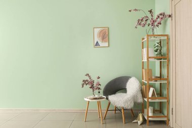 Odanın içinde çiçek açan dallarla dolu bir kitaplık.