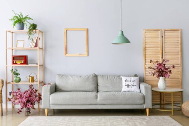 Oturma odasının içinde vazolar ve çiçek açan dallar var.