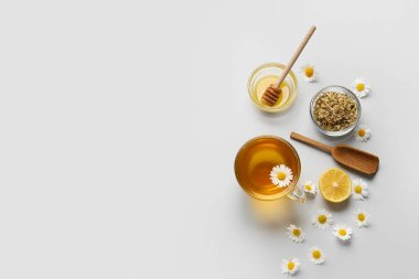 Lezzetli papatya çayı, çiçekler ve ballı kompozisyon gri arka planda