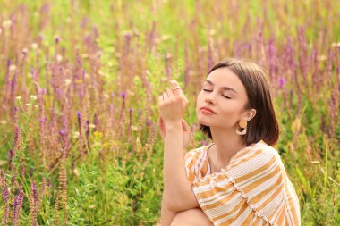 Çiçek açan alanda dinlenen güzel genç bir kadın.