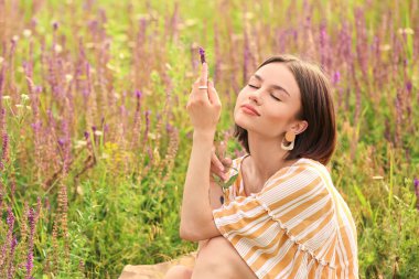 Çiçek açan alanda dinlenen güzel genç bir kadın.