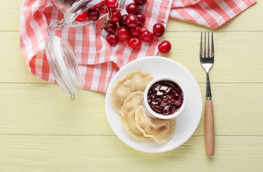 Lezzetli kirazlı hamur tatlısı ve ahşap arkaplanlı sos tabağı.