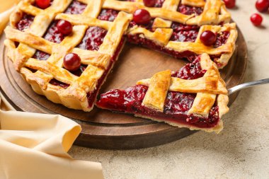 Açık arkaplanda lezzetli vişneli turta olan tahta, yakın plan.