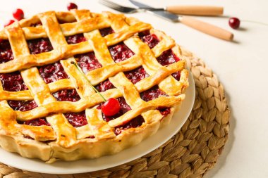 Hafif arka planda vişneli turta ve çatal bıçaklı tabak, yakın plan.