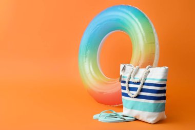 Renk arkaplanında şişirilebilir halka, torba ve parmak arası terlikler