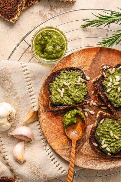 Tasty toasts with pesto sauce on color background