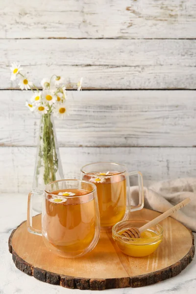 Glazen Kopjes Lekkere Kamillethee Bloemen Honing Een Lichte Houten Ondergrond — Stockfoto