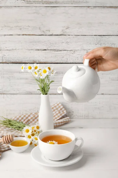 Vrouw Gieten Smakelijke Kamille Thee Van Theepot Kopje Lichte Houten — Stockfoto