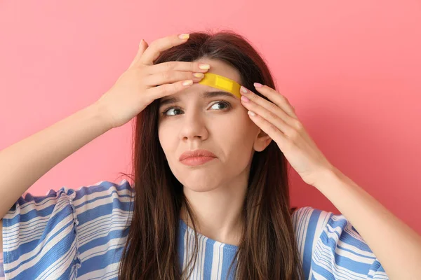 Displeased Young Woman Medical Patch Her Forehead Color Background — Stock Photo, Image