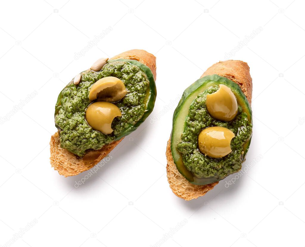 Tasty toasts with pesto sauce and olives on white background