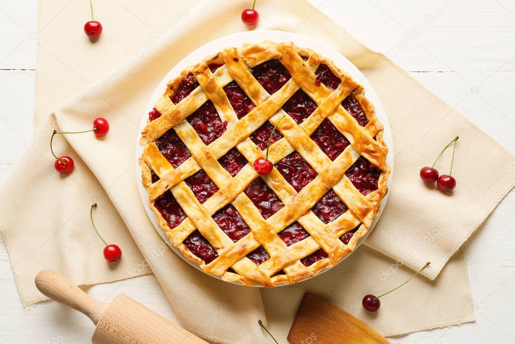 Tasty cherry pie and rolling pin on light wooden background