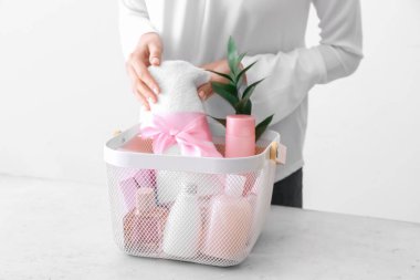 Kadın arka planda hediye sepetine havlu koyuyor.