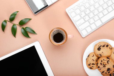 Bir fincan kahve, tablet bilgisayar, klavye ve renkli kurabiyeler.