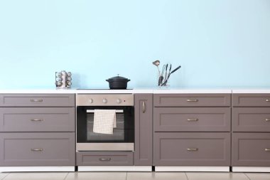 Renkli duvarın yanında elektrikli fırın olan modern mutfak tezgahı.