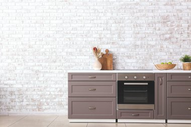 Duvarın yanında elektrikli fırın olan modern mutfak tezgahı.