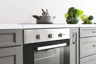 Işık duvarının yanında elektrikli fırını olan modern mutfak tezgahı.