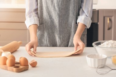 Mutfakta puf hamuru ve malzemeleri olan bir kadın.