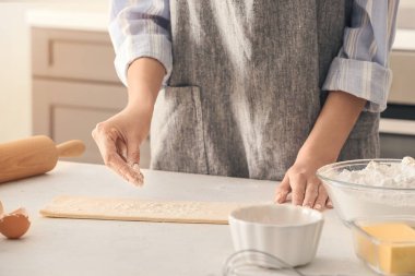 Mutfak masasına un serpiştiren kadın.