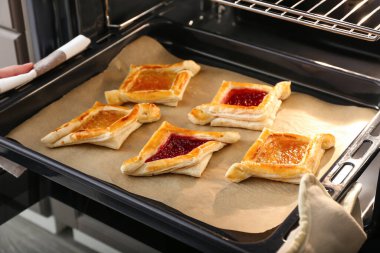 Kadın fırından fırın tepsisini Danimarka pastasıyla çıkarıyor, yakın plan.