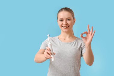 Diş fırçası olan genç bir kadın, arka planda iyi görünüyor.