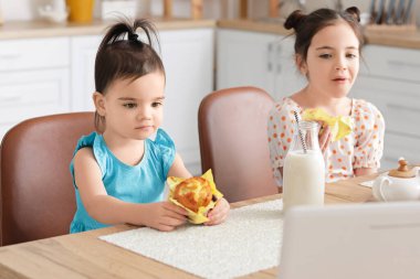 Sevimli küçük kız kardeşler mutfakta atıştırmalık yiyor.