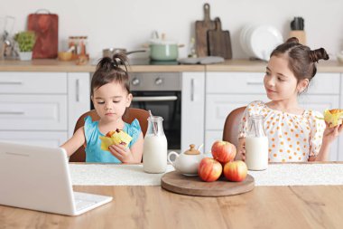 Sevimli küçük kız kardeşler mutfakta atıştırmalık yiyor.