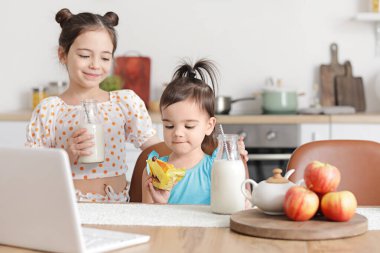 Sevimli küçük kız kardeşler mutfakta atıştırmalık yiyor.