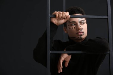 Siyah arka planda yüzü boyalı genç bir Afro-Amerikalı.