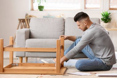 Genç adam evde mobilya montajı yapıyor.