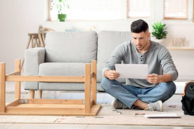 Genç adam evde mobilya montajı yapıyor.