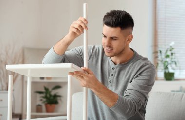 Genç adam evde mobilya montajı yapıyor.