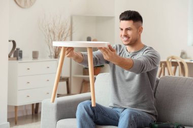 Genç adam evde mobilya montajı yapıyor.