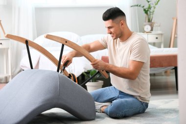 Genç adam evde mobilya montajı yapıyor.