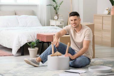 Genç adam evde mobilya montajı yapıyor.