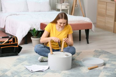 Evde mobilya montajlayan genç bir kadın.