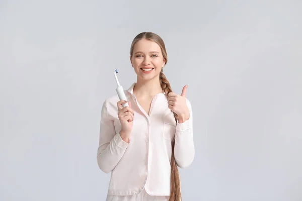 歯ブラシを持つ若い女性は灰色の背景に親指アップを表示 — ストック写真