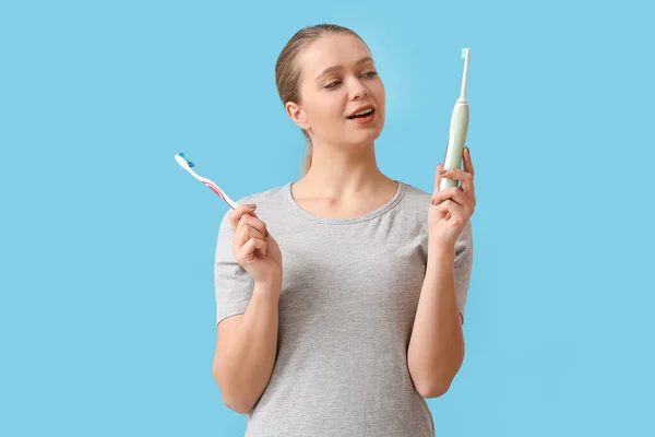 Young woman with tooth brushes on color background