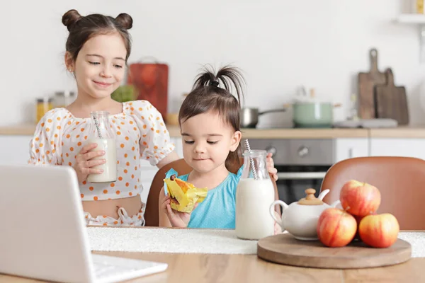 Sevimli küçük kız kardeşler mutfakta atıştırmalık yiyor.