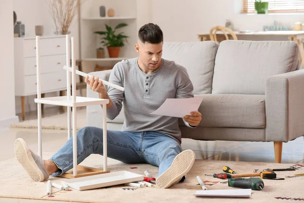 Genç adam evde mobilya montajı yapıyor.