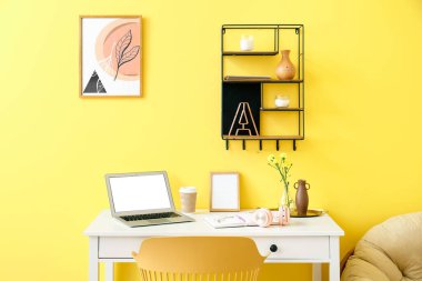 Renk duvarının yanında dizüstü bilgisayarı olan modern işyeri