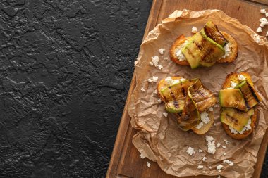 Peynirli lezzetli bruschettalar ve koyu arkaplanda ızgara kabak, yakın plan.