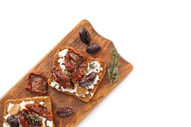 Peynirli lezzetli bruschettalar, güneşte kurutulmuş domatesler ve beyaz arka planda hurma, yakın plan.