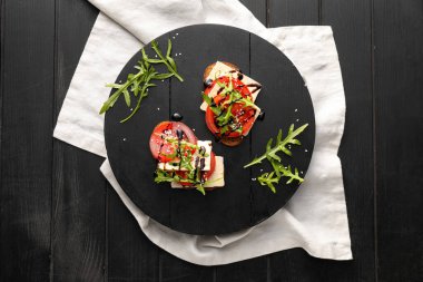 Koyu ahşap arka planda domates ve tofu peynirli lezzetli bruschettalar.